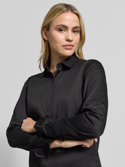 Frauenmodel trägt Hemdbluse aus Baumwoll-Mix Modell 'Mattie' von MOS MOSH in Schwarz mit Rüschenärmeln, Nahaufnahme Oberkörper. Slim Fit, durchgehende Knopfleiste, Hemdblusenkragen, elastischer Baumwoll-Mix, schlichter Look.