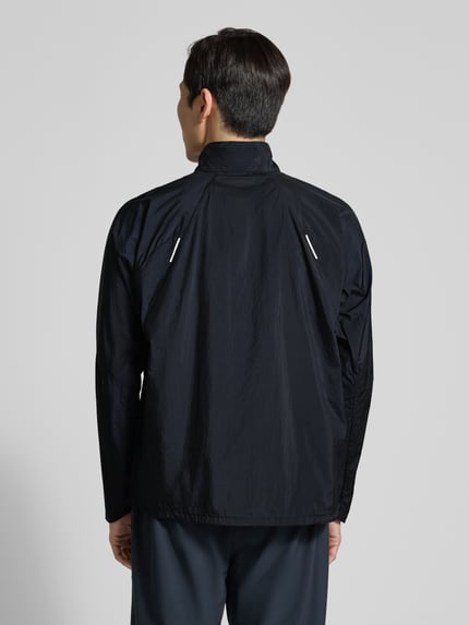 Męski model nosi Jacke mit Stehkragen und Logo od Salomon, czarny kolor, krój regular fit, widok całej sylwetki od tyłu. Długość pleców w rozmiarze M: 70 cm, szerokość ramion w rozmiarze M: 42 cm, szerokość klatki piersiowej w rozmiarze M: 61 cm, długość rękawa w rozmiarze M: 66 cm.