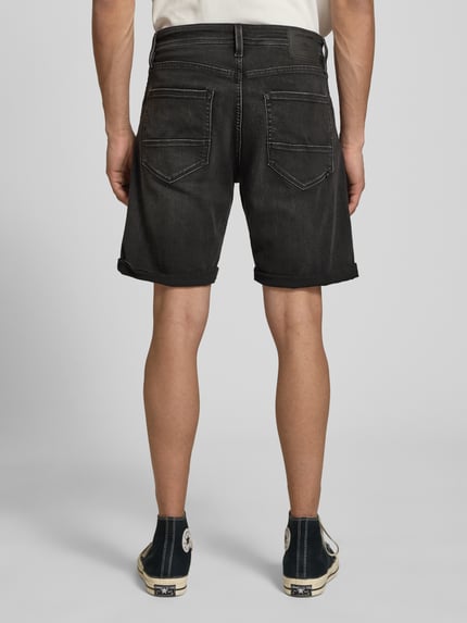 Männermodel trägt Jeansshorts mit Umschlag Modell 'RICK' von Jack & Jones aus Baumwoll-Mix mit Stretch-Anteil, Regular Fit, Ganzkörperansicht Rückansicht.