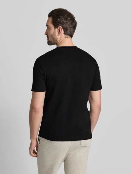 Mężczyzna nosi T-Shirt z label-stitching model 'Austin' od HUGO, bawełniany czarny materiał, regular fit, widok całej sylwetki z tyłu.