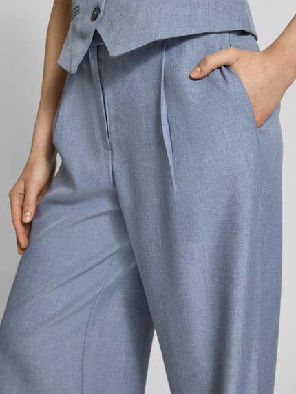 Kobiece model nosi Regular Fit Weite Hose mit Schiebehakenverschluss Modell 'LINDA' od ONLY, melanżowy efekt, wpuszczane kieszenie, krój regular fit, szlufki na pasek, zapięcie na haftkę, guzik i ukryty zamek błyskawiczny, detal wpuszczanych kieszeni, wpuszczane kieszenie z efektem melanżu, zbliżenie na górną część spodni