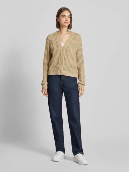 Frauenmodel trägt Relaxed Fit Cardigan in Strick-Optik Modell 'CHARLIE' von NOISY MAY®, beige, grobe Struktur, V-Ausschnitt, Ganzkörperansicht von vorne.