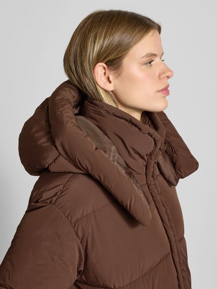 Frauenmodel trägt Regular Fit Steppjacke mit Kapuze Modell 'CORNELIA' von Only, unifarben braun, Nahaufnahme Oberkörper.