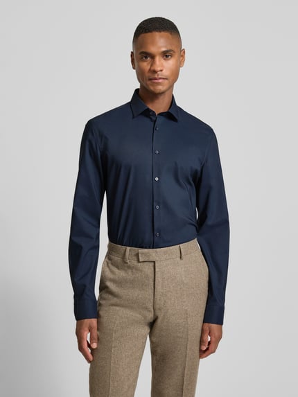 Männermodel trägt Super Slim Fit Business-Hemd mit Kentkragen von Jake*s in Dunkelblau, Material-Mix mit Stretch, Ganzkörperansicht von vorne.