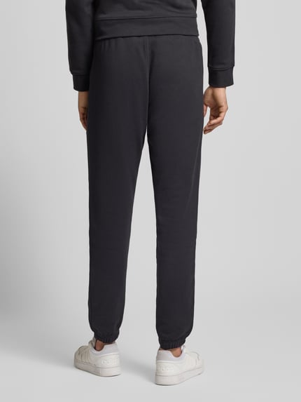 Männermodel trägt Sweatpants mit Label-Stitching und elastischem Bund von adidas Originals, czarny kolor, bawełna, regular fit, ganzkörperansicht rückansicht.