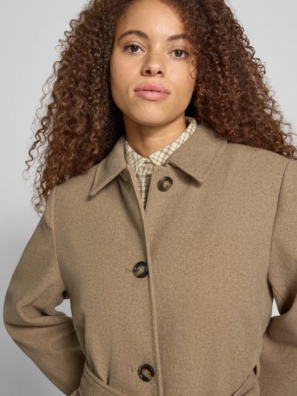 Frauenmodel trägt Teddymantel mit Bindegürtel von PIECES in unifarbener Strukturoptik mit Umlegekragen und Zierknöpfen, Nahaufnahme Oberkörper.
