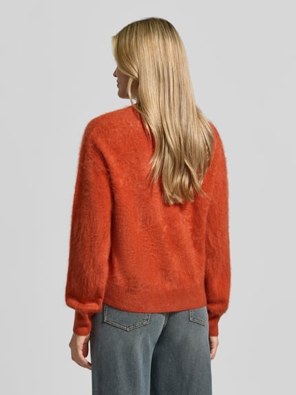 Frauenmodel trägt Regular Fit Pullover aus reinem Kaschmir von Jake*s Casual in warmem Orange, weiche Textur, Ganzkörperansicht Rückansicht.