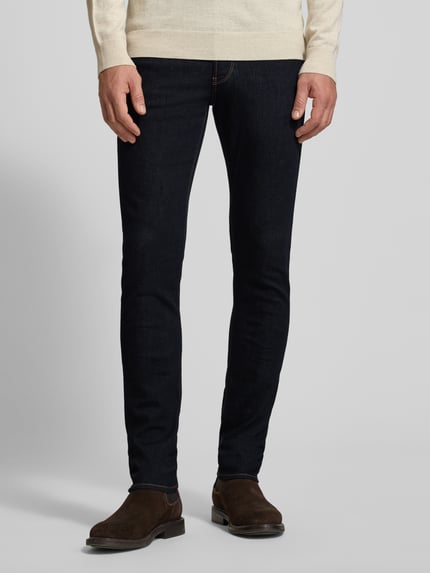 Männermodel trägt Slim Fit Jeans mit Logo-Applikation von Emporio Armani in dunklem Blau, 5-Pocket-Design, Nahaufnahme Unterkörper, Vorderansicht.