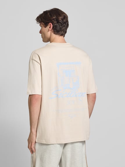 Männermodel trägt Oversized T-Shirt mit rückseitigem Print Modell 'Pedroche' von Pegador in Beige, Reine Baumwolle, Ganzkörperansicht Rückansicht.