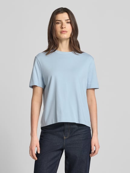 Frauenmodel trägt Boxy Fit T-Shirt aus reiner Baumwolle Modell 'ESSENTIAL' von Selected Femme in Optik: Unifarben, Label-Patch am Saum, Rundhals, Ärmelform: Kurzarm, Materialverarbeitung: Heavy Jersey, Farbe hellblau, glatte Textur, Ganzkörperansicht von vorne.