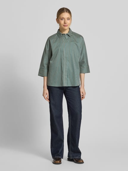 Frauenmodel trägt Regular Fit Hemdbluse mit durchgängiger Knopfleiste von Christian Berg Woman, Reine Baumwolle, Halbarm, Hemdblusenkragen, dunkelgrün mit weißen Streifen, Rückenlänge 64 cm, Ärmellänge 46 cm, Ganzkörperansicht von vorne.