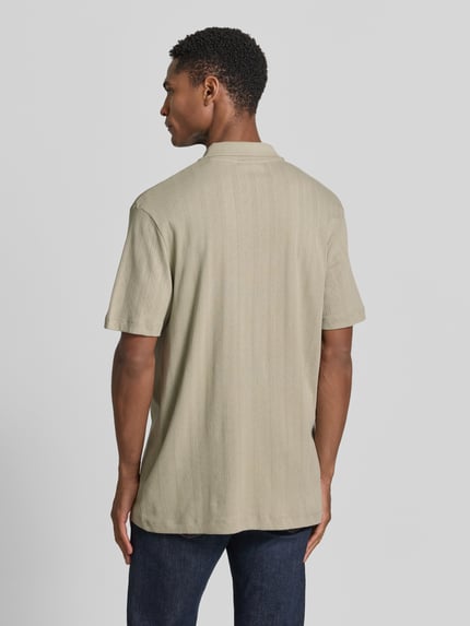 Männermodel trägt Regular Fit Poloshirt mit kurzer Knopfleiste von Lindbergh aus Reine Baumwolle mit Jaquard-Strick, Rückenlänge 70 cm, Ganzkörperansicht Rückansicht.