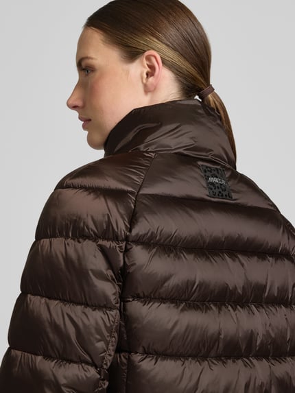Frauenmodel trägt Steppjacke mit Stehkragen und Label-Detail von Marc Cain in Braun, glänzende Oberfläche, Kontext: Damen Steppjacke Regular Fit, Eingrifftaschen, Rückenlänge 56 cm, Schulterbreite 41 cm, Brustweite 55 cm, Ärmellänge 73 cm, Nahaufnahme Oberkörper Rückansicht.
