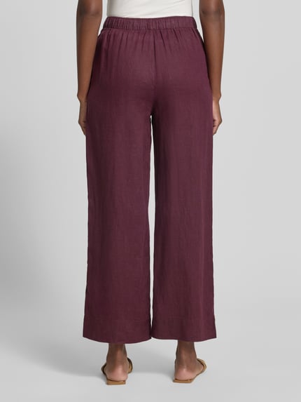 Frauenmodel trägt Stoffhose mit elastischem Bund Modell 'LINO' von Mango aus Material-Mix mit Baumwoll-Anteil, Wide-Leg, Ganzkörperansicht Rückansicht.