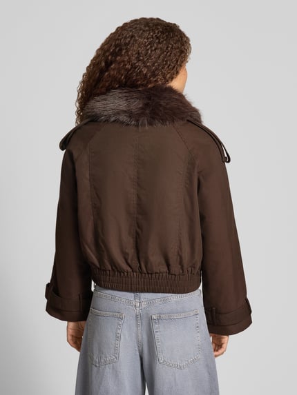 Vrouwenmodel draagt Regular Fit Jacke met Kunstpelz van Gina Tricot, katoenmix, donkerbruin, elastische band, schoudertrensjes, mouwsluitingen, reverskraag, dubbele knoopsluiting, ruglengte maat S 50 cm, schouderbreedte 50 cm, borstwijdte 58 cm, mouwlengte 53 cm, volledig zichtbare achterkant, KI-modified afbeelding. Ganzkörperansicht Rückansicht