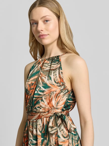 Frauenmodel trägt Maxikleid mit floralem Allover-Print von Apricot in Orange-Grün-Tönen, taillierte Passform, ärmellos, Nahaufnahme Oberkörper.