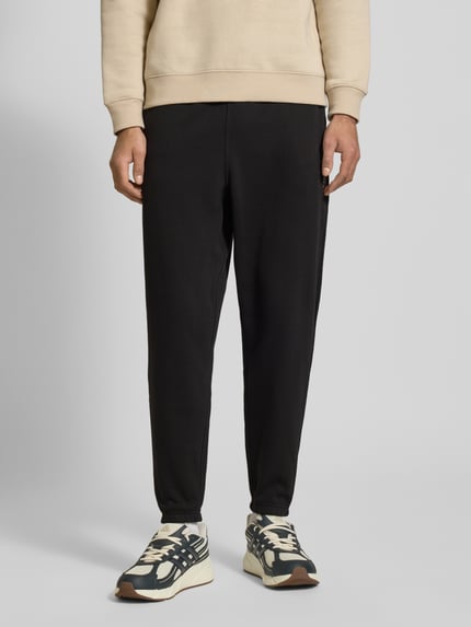 Männermodel trägt Regular Fit Sweatpants aus Baumwoll-Mix von Tommy Jeans, Optik: Unifarben, Materialverarbeitung: Sweat, Ganzkörperansicht von vorne.
