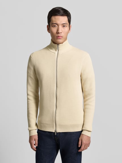 Männermodel trägt Regular Fit Strickjacke aus reiner Baumwolle Modell 'DAME' von SELECTED HOMME in uni beige, Ganzkörperansicht von vorne.