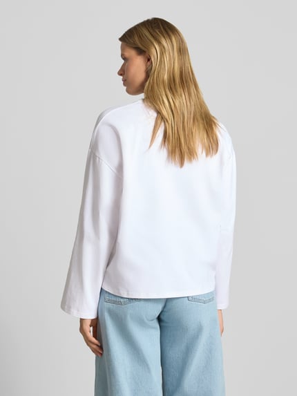 Frauenmodel trägt Oversized Langarmshirt aus reiner Baumwolle von REVIEW in Weiß mit rundem Ausschnitt, Rückenansicht, Ganzkörperansicht Rückansicht, Damen Langarmshirt, Oversized Fit, überschnittene Schultern, Rückenlänge bei Größe S 58 cm.