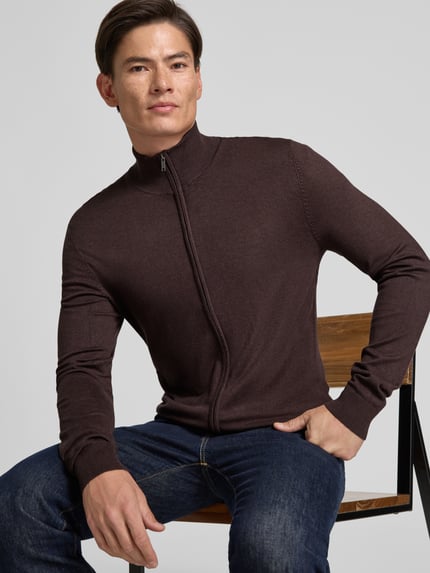 Männermodel trägt Slim Fit Strickjacke aus Viskose-Mix mit Stehkragen von MCNEAL in Dunkelbraun, Reißverschluss, Nahaufnahme Oberkörper.