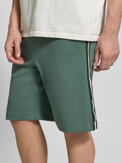 Männermodel trägt grüne Shorts mit elastischem Bund von EA7 Emporio Armani, Baumwoll-Mix, Regular Fit, Nahaufnahme Oberkörper.