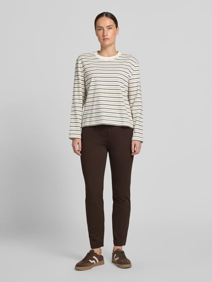 Frauenmodel trägt Loose Fit Bundfaltenhose aus Viskose-Mix von Tom Tailor in Dunkelbraun, kombiniert mit gestreiftem Oberteil, Ganzkörperansicht von vorne, Damen Bundfaltenhose von Tom Tailor.