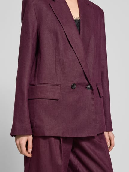 Frauenmodel trägt Blazer mit Pattentaschen Modell 'TEMPOLI' von Mango aus Reines Leinen, Gerader-Schnitt, Reverskragen, Knopfverschluss, Nahaufnahme Oberkörper.