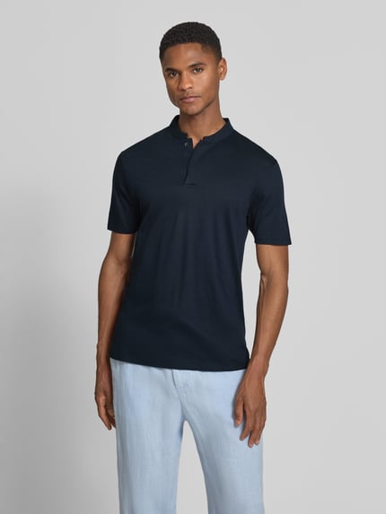 Männermodel trägt Slim Fit Poloshirt mit Stehkragen Modell 'LOUIS' von Drykorn aus Baumwoll-Modal-Mix in Dunkelblau, Ganzkörperansicht von vorne. Rückenlänge bei Größe M: 69 cm.