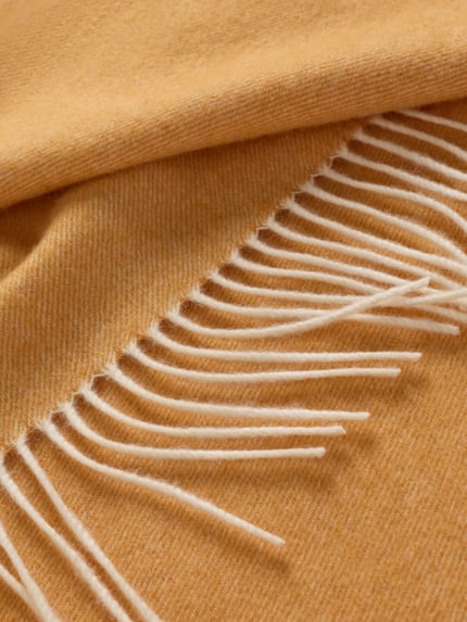 Produktfoto, Wollschal mit Kaschmir-Anteil von Ascot in warmem Gelbton, Strick-Optik, Fransen, rechteckige Form, weiche Textur.