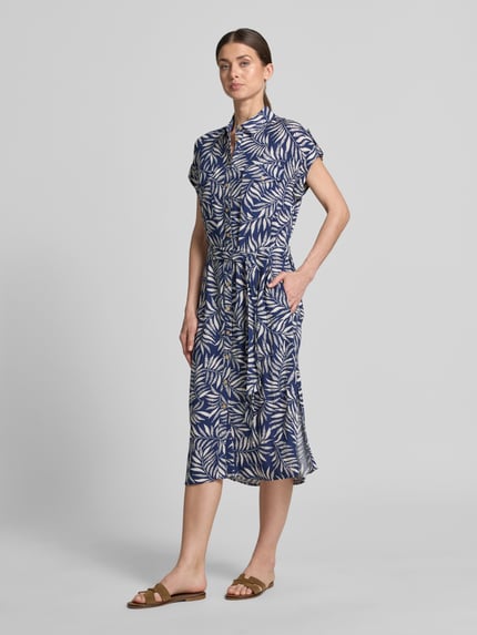 Vrouwenmodel draagt Hemdblusenkleid aus Viskose mit Brusttaschen van Apricot in blauw met wit bladmotief, getailleerd model, midi-jurk, overhemdkraag, knoopsluiting, korte mouwen met vaste omslag, borstzakken met knoopsluiting, strikceintuur, ruglengte maat S 118 cm, borstwijdte 49 cm, mouwlengte 5 cm, geheelbeeld van voren.