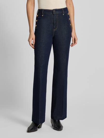 Frauenmodel trägt High Waist Palazzo Jeans mit seitlichen Knöpfen von GUESS aus Baumwoll-Mix mit Modal-Anteil, dunkelblau, Ganzkörperansicht von vorne.