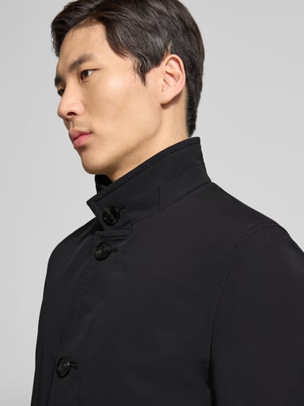 Männermodel trägt Regular Fit Kurzmantel mit Stehkragen Modell 'FYNN' von Strellson in Schwarz, glatte Twill-Textur, Nahaufnahme Oberkörper.