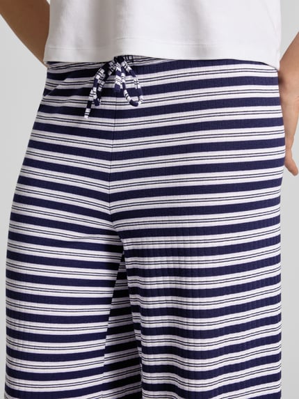 Frauenmodel trägt Hose im Allover-Look mit Tunnelzug von Gina Tricot, Material-Mix mit Viskose-Anteil, Nahaufnahme Oberkörper.