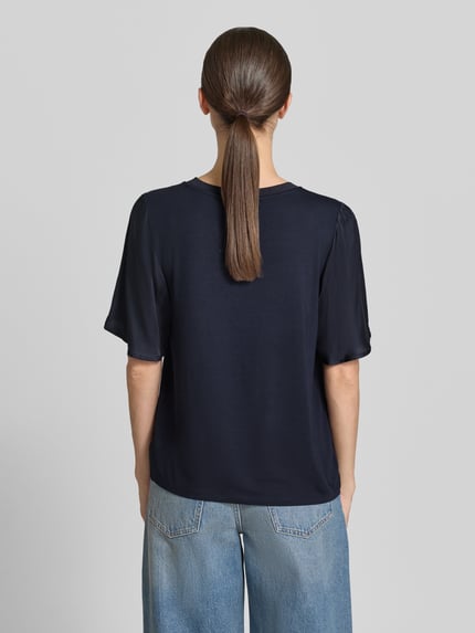 Frauenmodel trägt T-Shirt aus Viskose-Mix mit Rundhalsausschnitt von Comma, Damen T-Shirt mit Stretch-Anteil, gerader Schnitt, 1/2-Arm, Rückenlänge 55 cm, dunkelblaue Farbe, glatte Textur, Ganzkörperansicht Rückansicht.