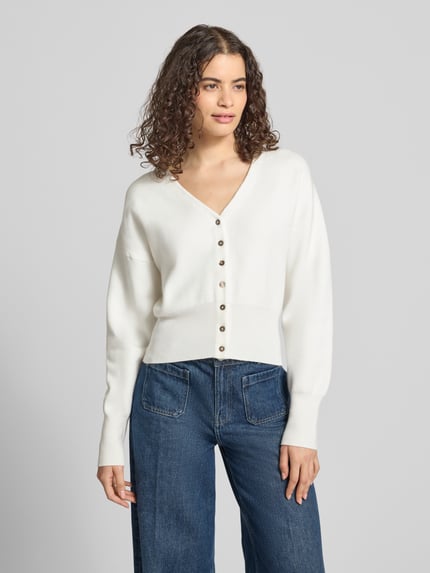 Modelka nosi kardigan z mieszanki bawełny i wiskozy, krój regular fit, model 'Compact' od Topshop, imitacja dzianiny, dekolt w serek, widok całej sylwetki z przodu.