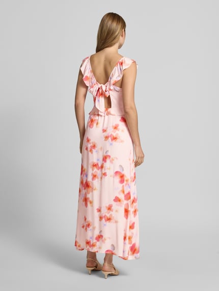 Vrouwenmodel draagt maxi-jurk uit zuiver viscose met volants model 'Callindra' van mbyM, A-lijn, V-hals, roze met oranje motief, ruglengte maat S 111 cm, borstwijdte maat S 34 cm. Ganzkörperansicht Rückansicht.