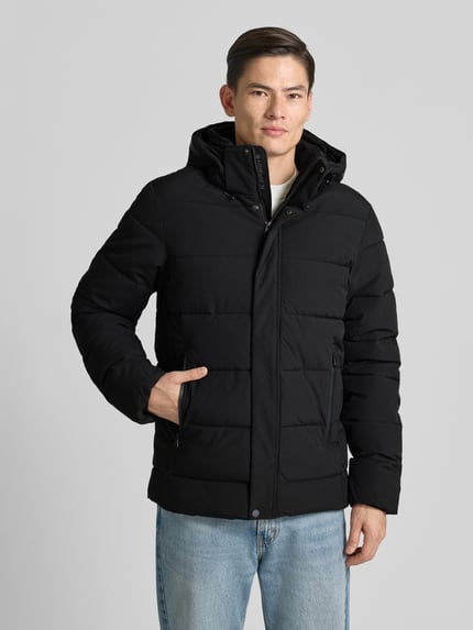 Mannelijk model draagt Steppjacke met capuchon model 'BIXBY' van Icepeak, zwart, regular fit, vooraanzicht hele lichaam. Regular fit, verborgen rits, ritssluitzakken, ruglengte maat 50: 78 cm, schouderbreedte: 50 cm, borstwijdte: 60 cm, mouwlengte: 70 cm.