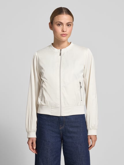 Frauenmodel trägt Jacke mit Rundhalsausschnitt und Reißverschlusstaschen von monari in Weiß, Regular-Fit, Ganzkörperansicht von vorne, Rückenlänge bei Größe 36: 52 cm, Schulterbreite: 46 cm, Brustweite: 53 cm, Ärmellänge: 57 cm.