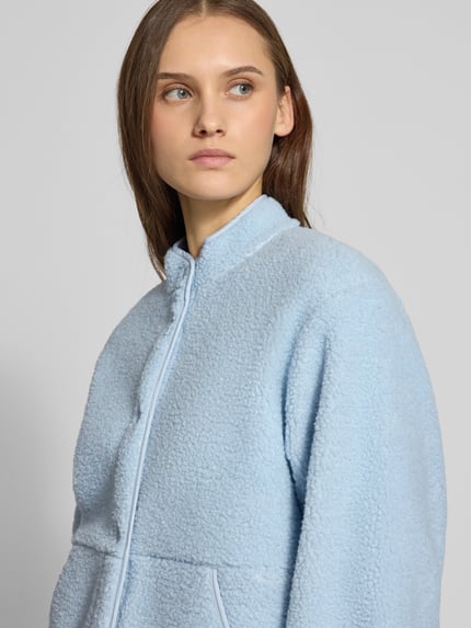 Kobiece modelka nosi Relaxed Fit Fleecejacke mit Stehkragen Modell 'VERA' od JJXX, jasnoniebieski teddy, rozpinana, nakładane kieszenie, kontekst: damska kurtka polarowa JJXX, długość tyłu w rozmiarze S: 57 cm, szerokość ramion w rozmiarze S: 41 cm, szerokość w biuście w rozmiarze S: 53 cm, długość rękawa w rozmiarze S: 54 cm, zbliżenie na górną część ciała