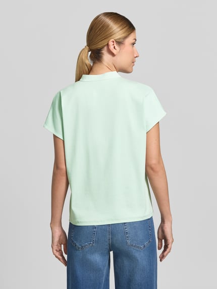 Männermodel trägt Regular Fit Bluse aus mieszanka bawełny z obszycie koronką od Marc Cain, kolor miętowy, krótkie rękawy, długość tyłu 57 cm w rozmiarze 36, widok całej sylwetki z tyłu.