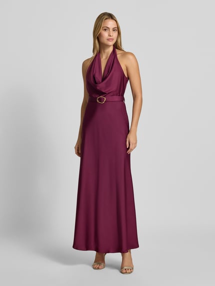 Frauenmodel trägt Abendkleid mit Neckholder von Rinascimento in dunklem Lila, Material-Mix mit Stretch, tailliert, Stoffgürtel, Maxikleid, Ganzkörperansicht von vorne.