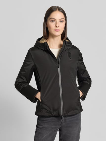 Frauenmodel trägt schwarze Regular Fit Jacke mit Logo-Detail Modell 'ERIE' von Blauer USA, Zweiwege-Reißverschluss, Kapuze, Ganzkörperansicht von vorne. Rückenlänge 63 cm, Schulterbreite 43 cm, Brustweite 50 cm, Ärmellänge 62 cm.