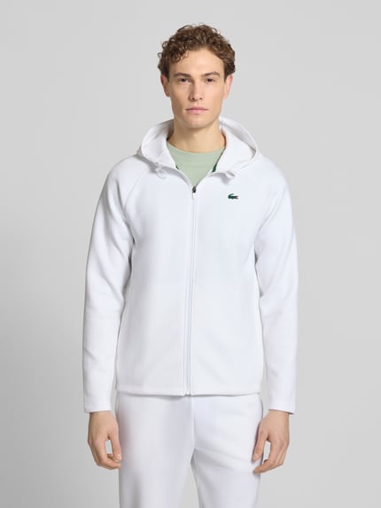 Mężczyzna model nosi Regular Fit Sweatjacke mit Baumwoll-Anteil od Lacoste Sport, gładka biel, bawełniany miks, z kapturem, widok z przodu, całe ciało.
