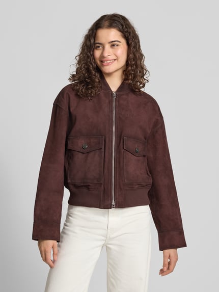 Frauenmodel trägt Regular Fit Leder- / Kunstlederjacke aus echtem Ziegenleder von Marc O'Polo DENIM in Dunkelbraun, glatte Textur, Ganzkörperansicht von vorne.