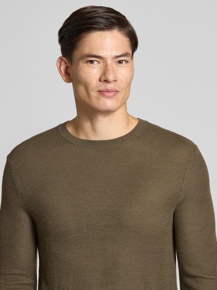 Männermodel trägt Strickpullover aus Wollmix Modell 'Bennino' von JOOP! COLLECTION in Olivgrün, unifarben, Nahaufnahme Oberkörper.