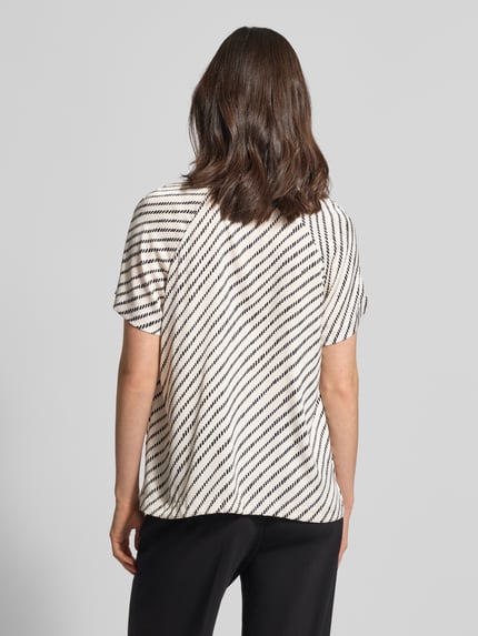Vrouwenmodel draagt Blusenshirt mit Schlüsselloch-Ausschnitt van comma, zwart-wit patroon, regular fit, materiaal-mix met stretch, allover-look, geplooide details, ruglengte 60 cm bij maat 36, mouwlengte 20 cm, achteraanzicht volledige lichaamsopname.