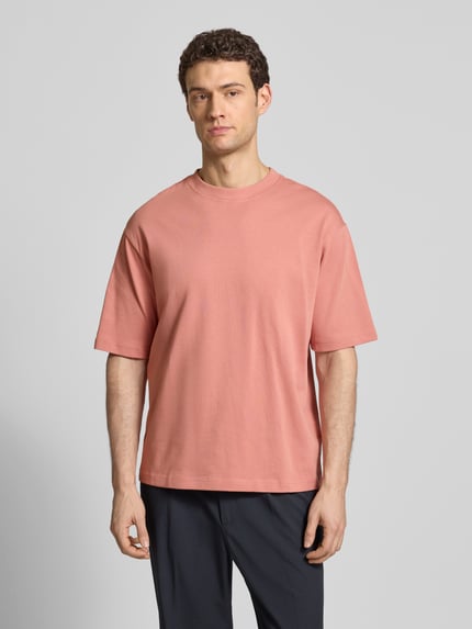 Männermodel trägt Relaxed Fit T-Shirt aus reiner Baumwolle Modell 'RELEXASPEN' von SELECTED HOMME, unifarben, Feinripp, Ganzkörperansicht von vorne.