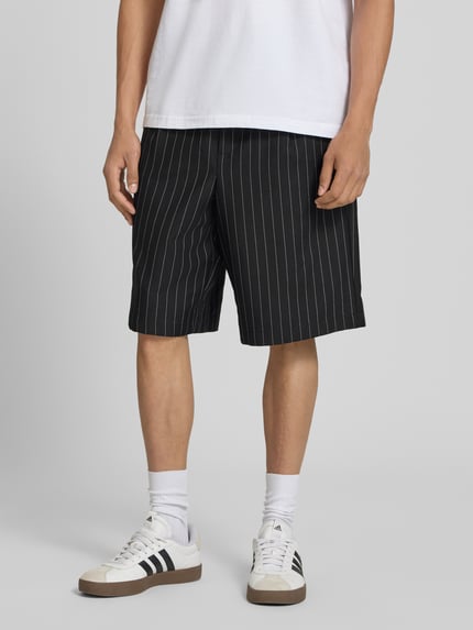 Mężczyznamodel nosi szorty z elastycznym pasem model 'CRISTIANO' od Redefined Rebel, mieszanka materiałów z dodatkiem streczu, krój relaxed fit, szerokość w rozmiarze M: 42 cm, długość wewnętrzna nogawki w rozmiarze M: 27 cm, widok na całe ciało z przodu.