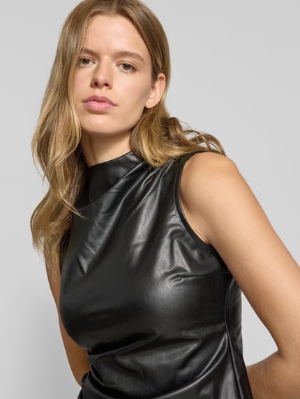 Vrouwenmodel draagt Top in leerlook met plooien model 'DANDY' van Noisy May, nauw aansluitend model, asymmetrische look, nahaufnahme bovenlichaam. Ruglengte maat S: 54 cm.