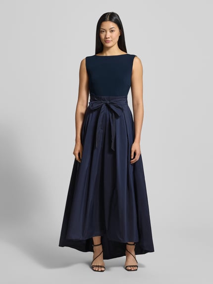 Frauenmodel trägt Abendkleid mit Bindegürtel und rückseitigem Reißverschluss von Christian Berg Cocktail, Material-Mix mit Stretch-Anteil, A-Linie, Midikleid, Rundhalsausschnitt, Ganzkörperansicht von vorne.